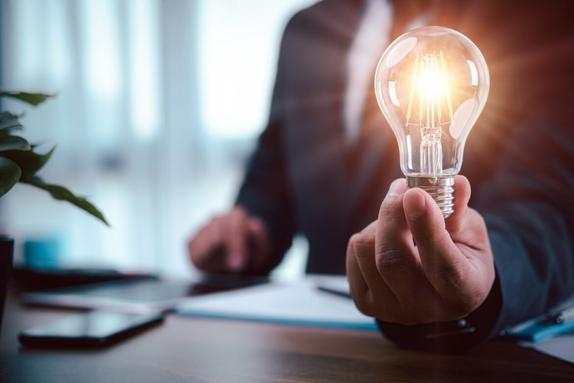 A hand holding a lit light bulb