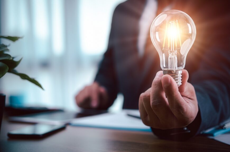 A hand holding a lit light bulb